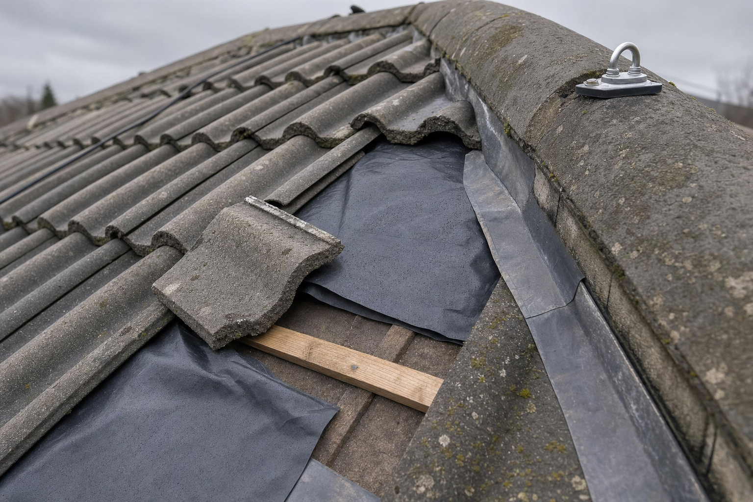 Partially repaired concrete roof tiles with visible underlay and timber battens.