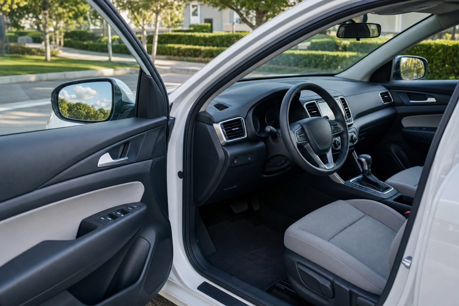 Open car door showing the driver's seat and interior dashboard on a sunny day.