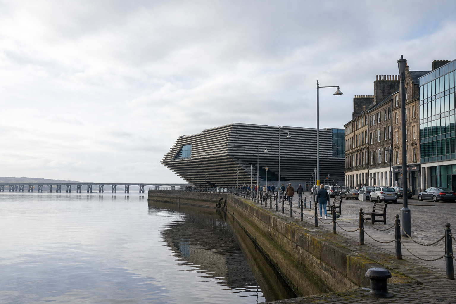 Modern waterfront building with a unique, angular design alongside a pier and historic architecture.