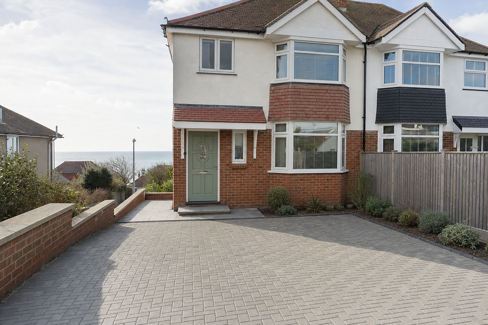 Semi-detached house with a large paved driveway and distant ocean view.
