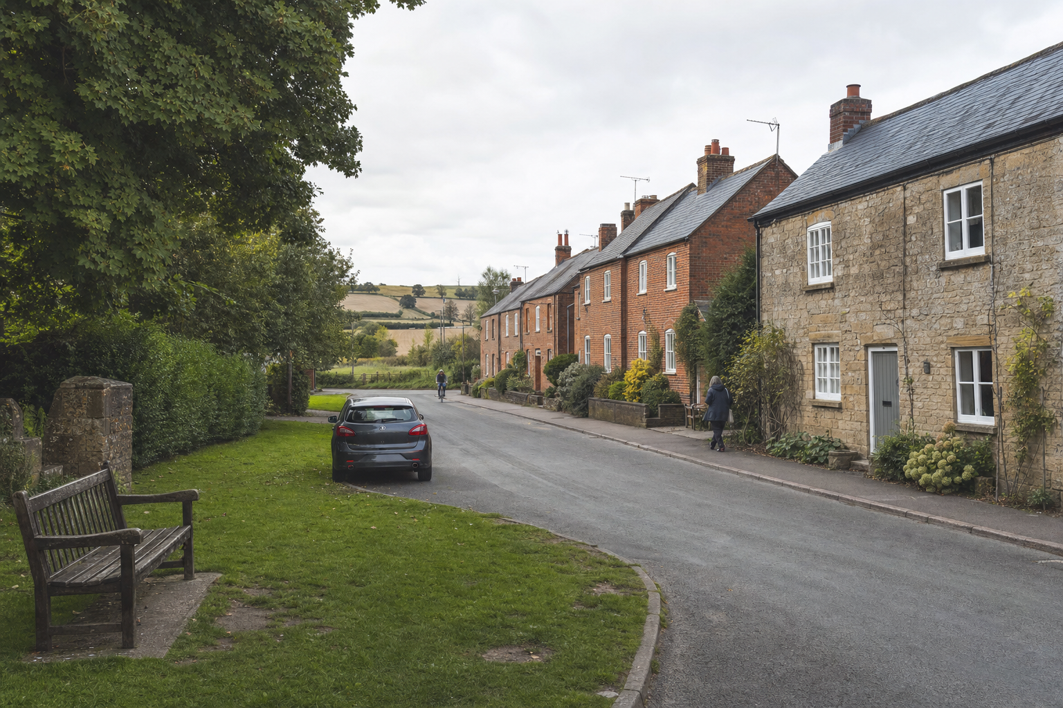 A quiet village street with stone and brick terraced houses, a car parked on the road, and a person walking and cycling nearby.