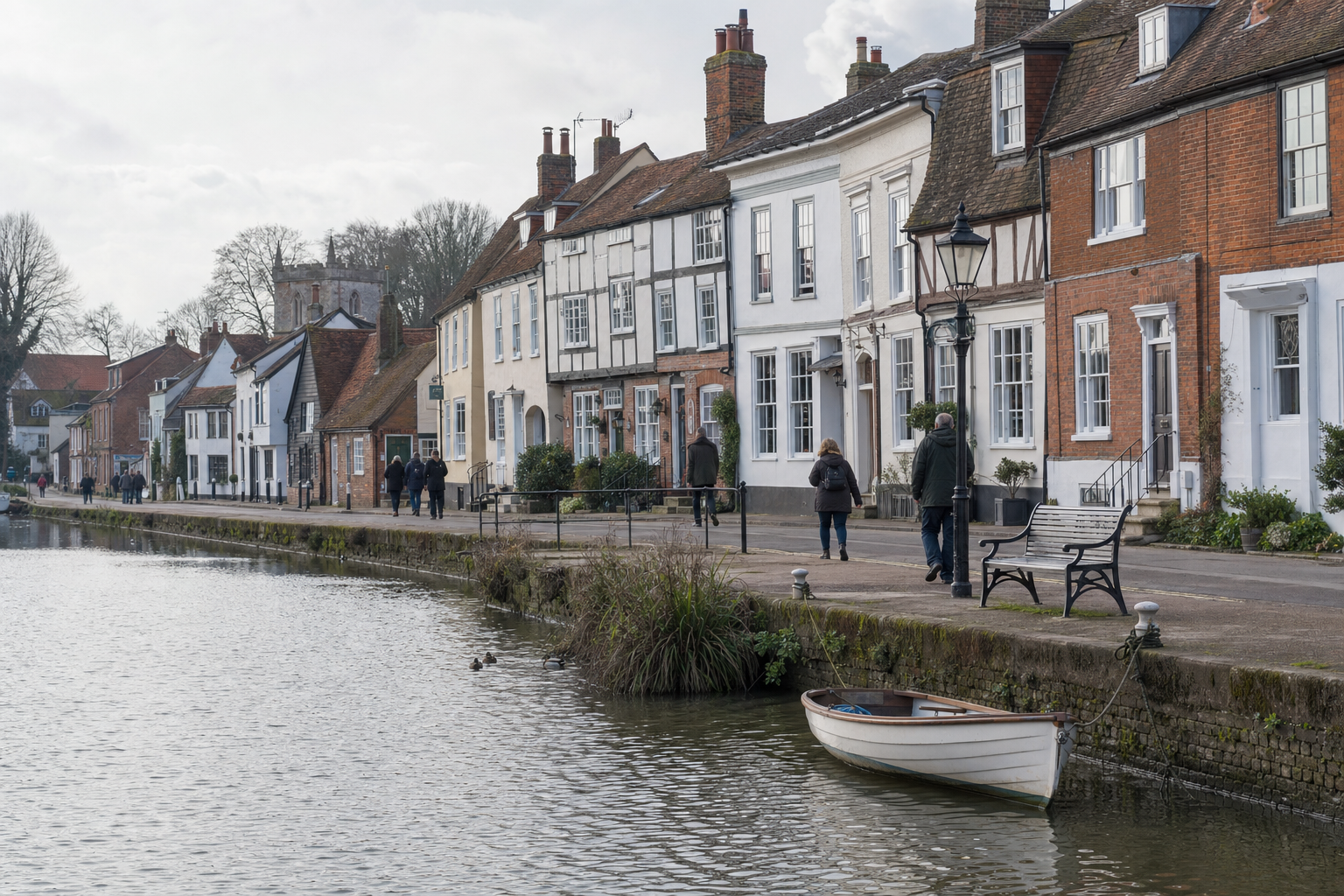 Canal-side view of historic terraced houses and a small boat on a cloudy day.