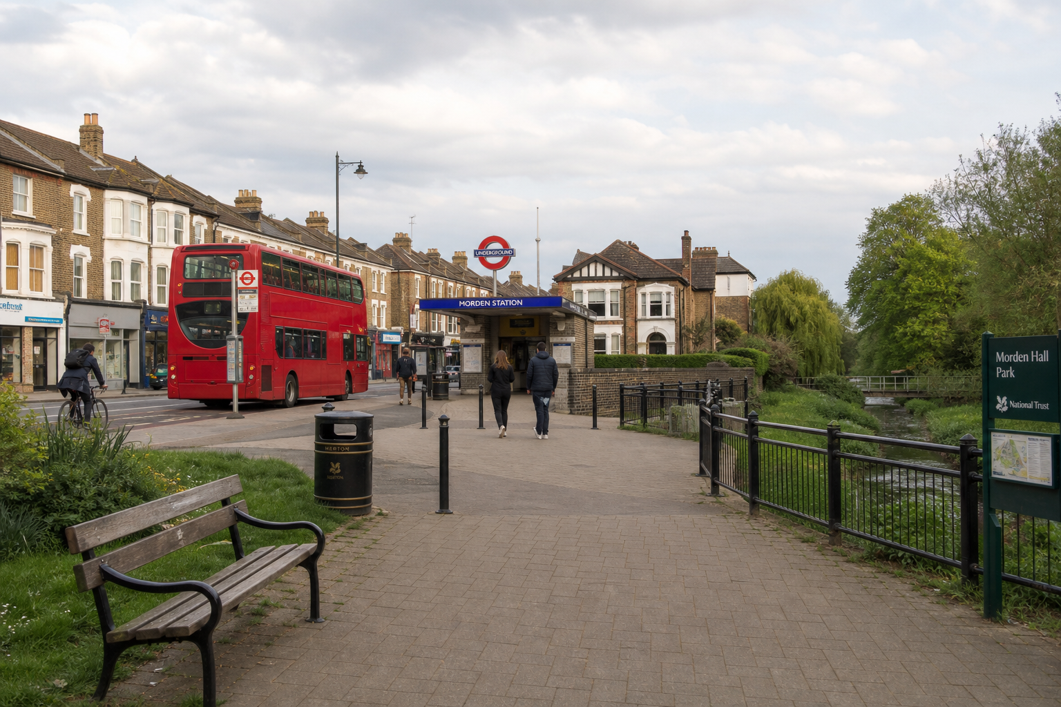 Greenwich underground station entrance with a red double-decker bus passing by and nearby.