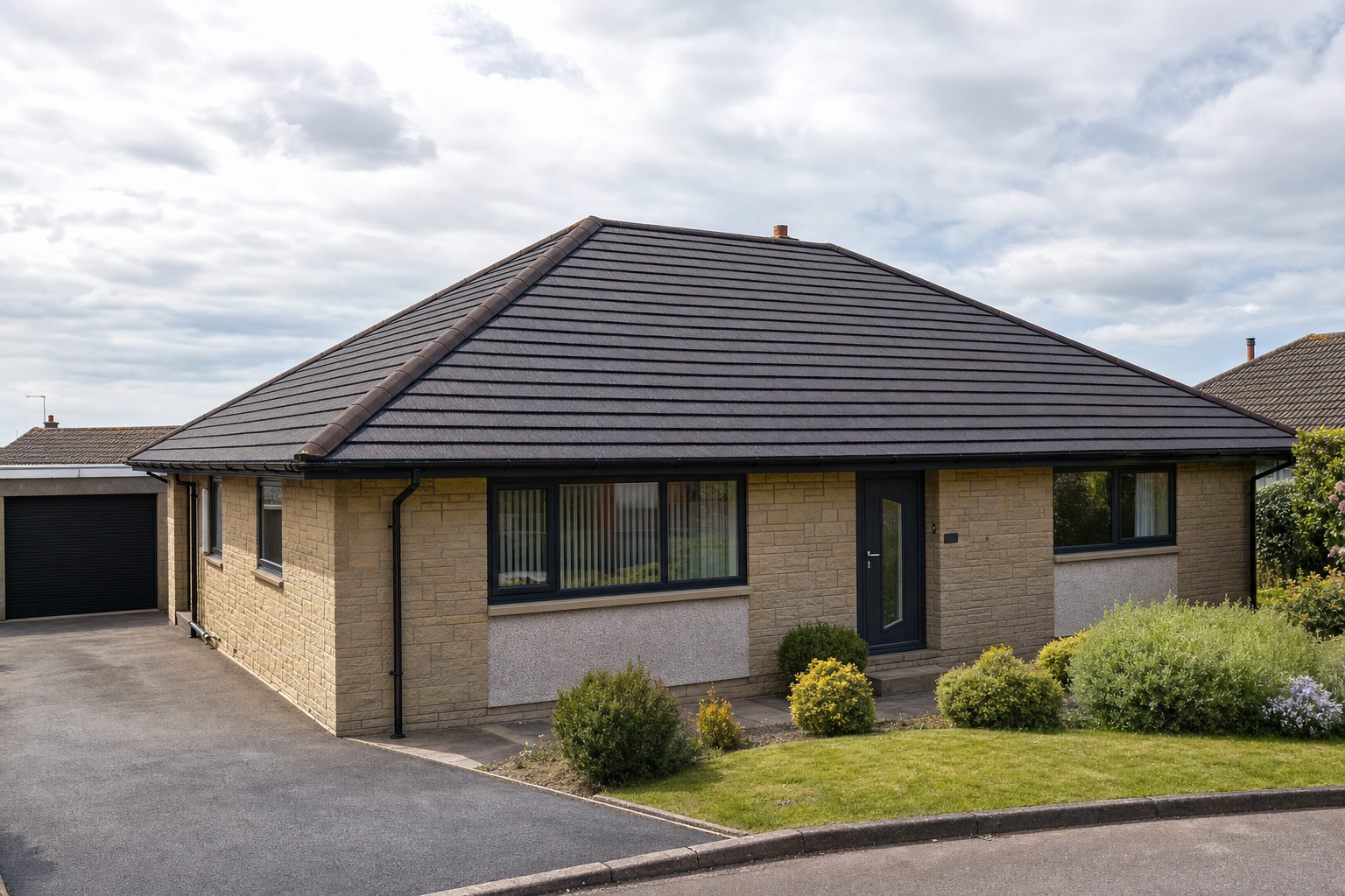 A detached bungalow with a slate roof and well-tended front garden under a cloudy sky.