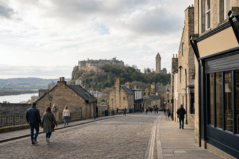 A cobbled street with people walking leads to a hilltop castle and tower under a cloudy sky.
