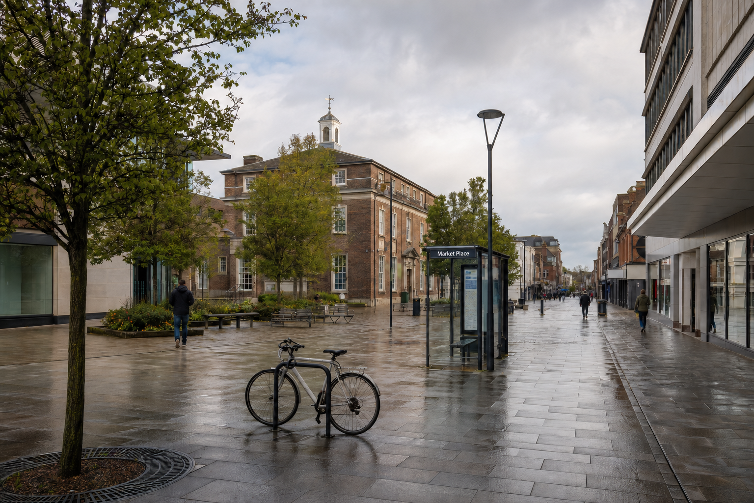 A quiet, wet pedestrian street with bicycles and a bus stop in front of a historic building.