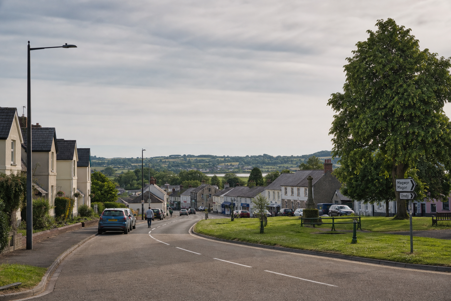 A quiet village street lined with houses and cars under a cloudy sky.