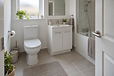 Modern bathroom with a white toilet, sink unit, and a bathtub with a shower, decorated with plants and towels.