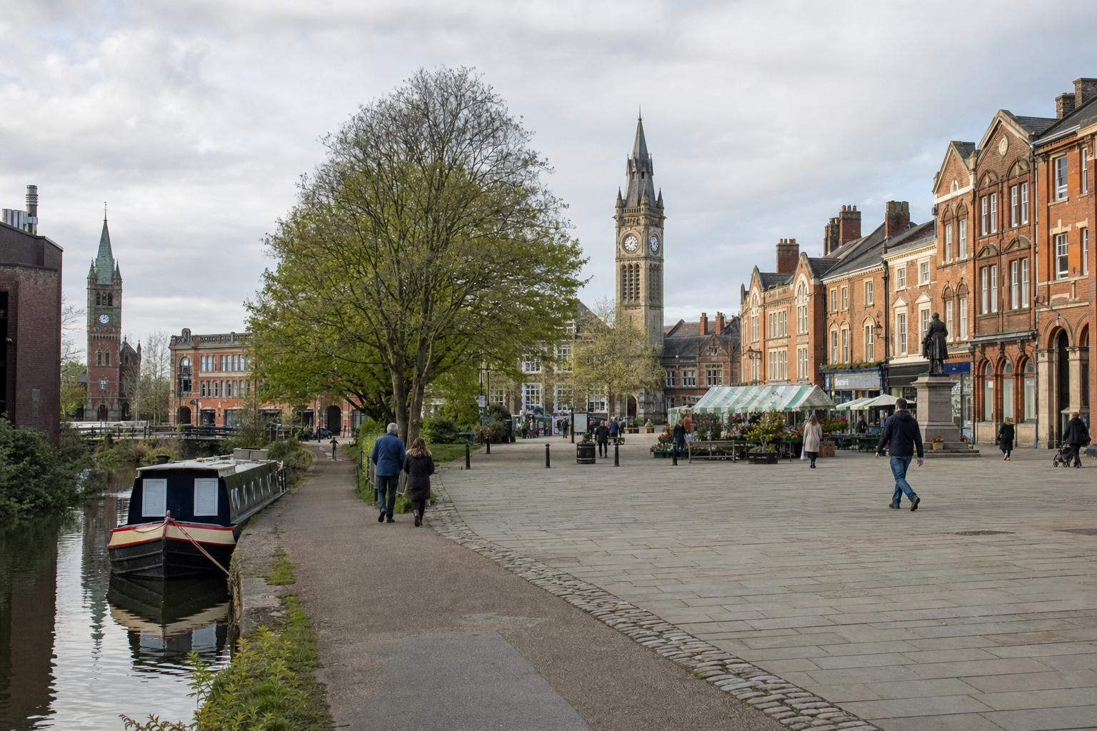 A canal boat moored alongside a tree-lined path in front of an English town square with clock towers and market stalls.