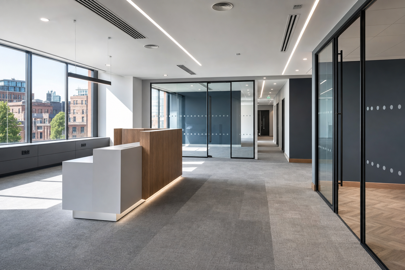 Modern office interior with large windows, glass partitions, and a sleek wooden reception desk.