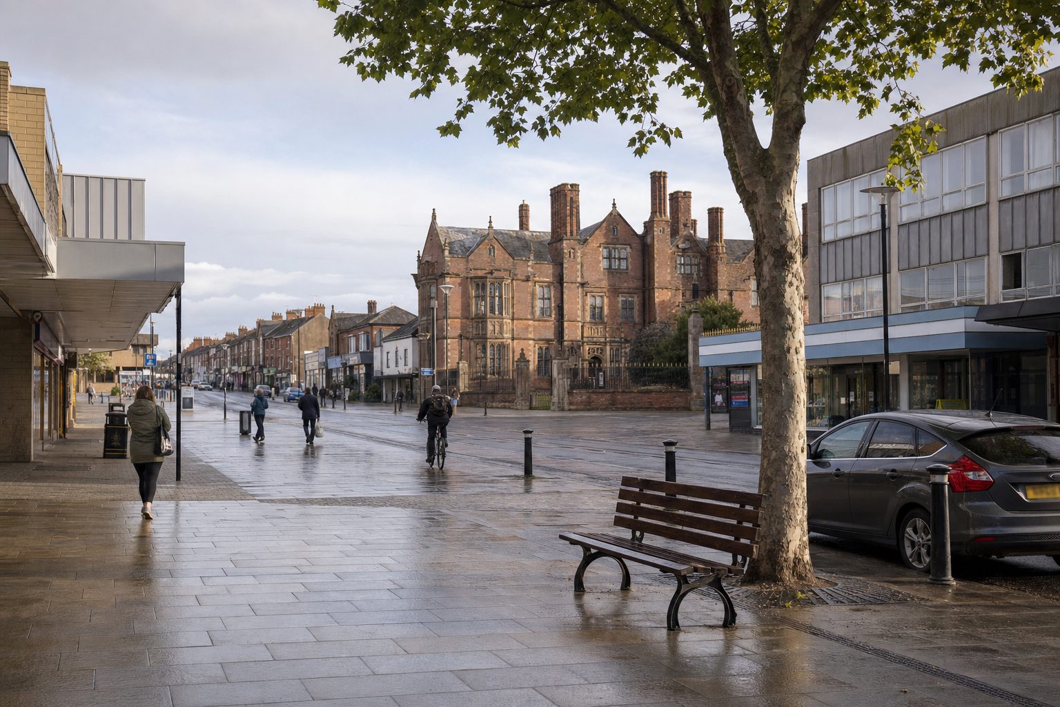 A rainy street scene in York with pedestrians, cyclists, and a historic building under a cloudy sky.
