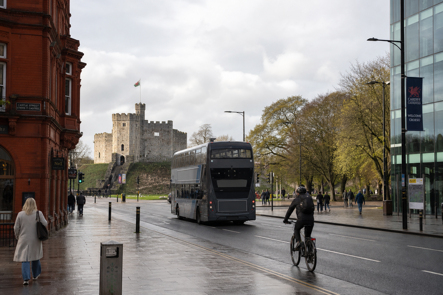 Double-decker bus and cyclist on Cardiff street, with Cardiff Castle in the background.