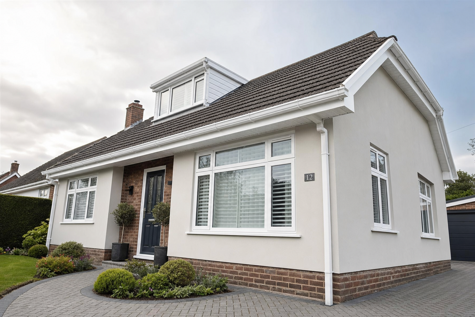 A modern bungalow with a sloped roof, surrounded by a tidy garden and paved driveway.