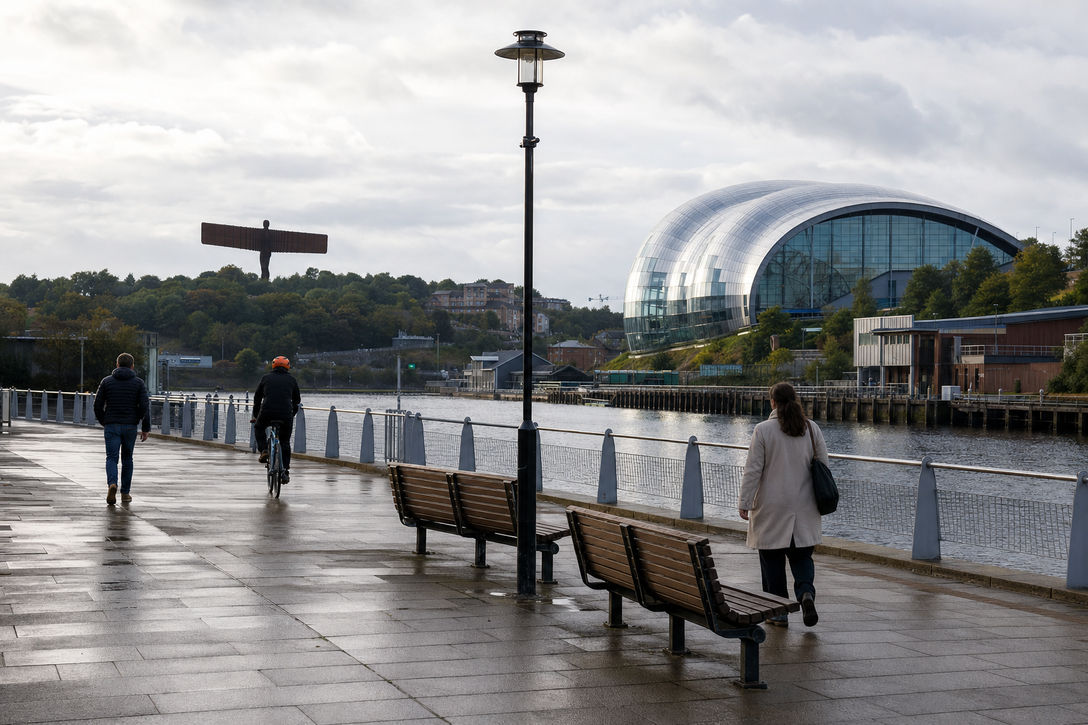 People walk and cycle along a riverside path, with the Sage Gateshead and the Angel of the North in the background.
