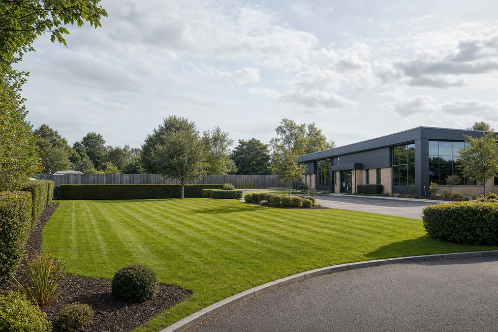 Modern office building with large windows, surrounded by a well-maintained lawn and neatly trimmed hedges under a cloudy sky.