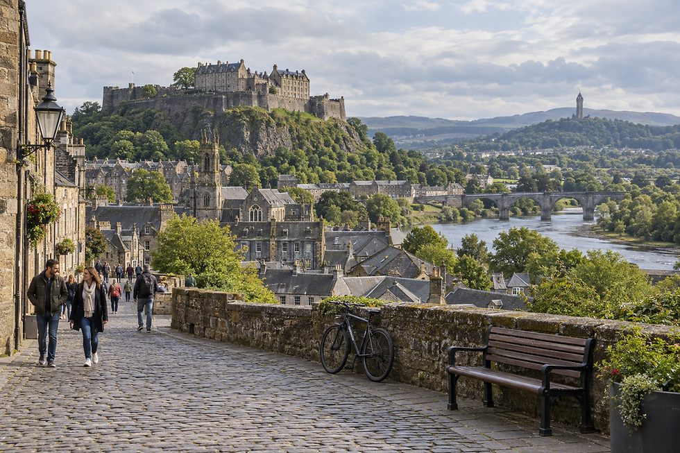 A cobbled street with people walking, bordered by historic buildings and a view of a castle on a hill.