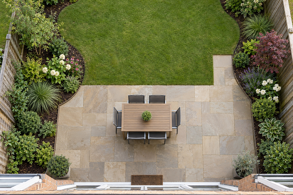 Aerial view of a garden with a lawn, patio, dining table, and surrounding flowers and shrubs.