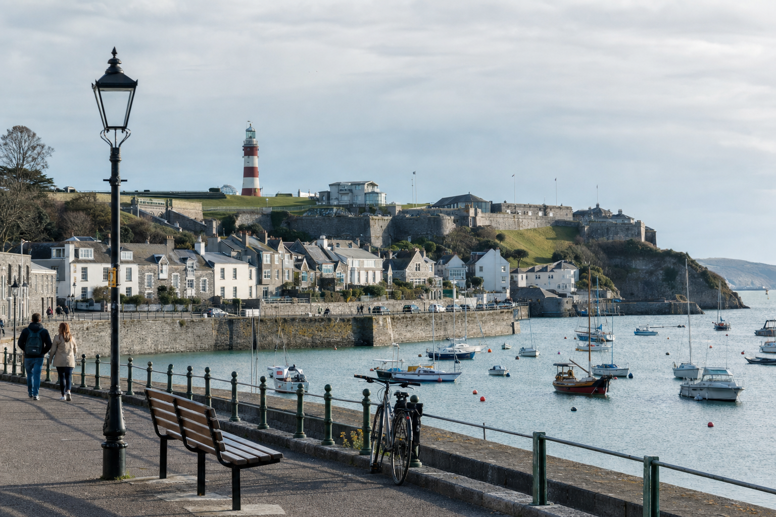 Coastal scene with a lighthouse, historic buildings, and boats in Plymouth, England.