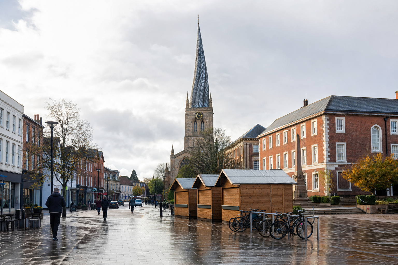 A cobbled street scene with a prominent church spire in the background, surrounded by red brick buildings and market stalls.