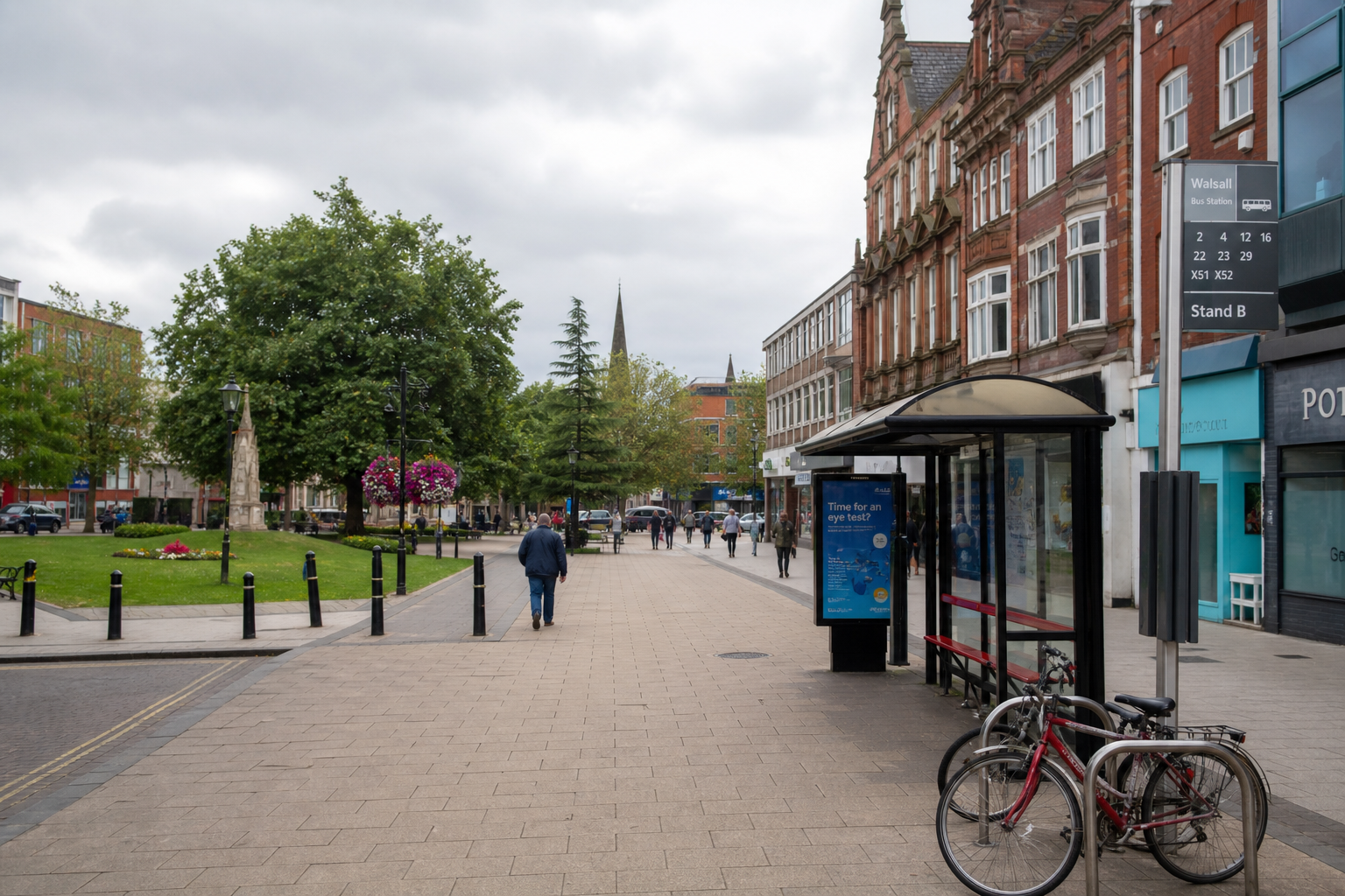 A pedestrian street scene with a bus stop, bicycles, historic buildings, trees, and people walking under a cloudy sky.