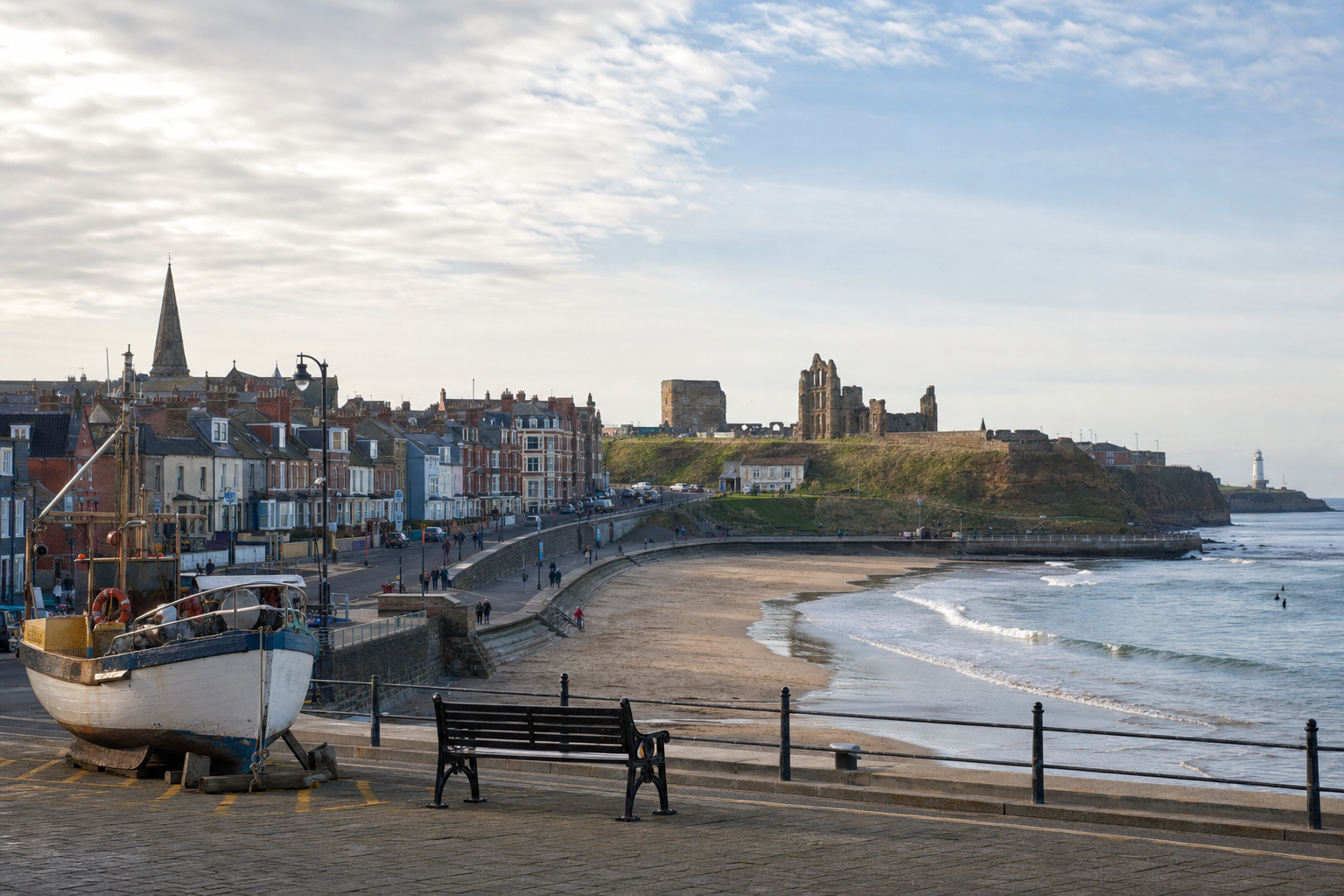 Coastal townscape featuring a moored boat, sandy beach, historic ruins, and a lighthouse under a cloudy sky.
