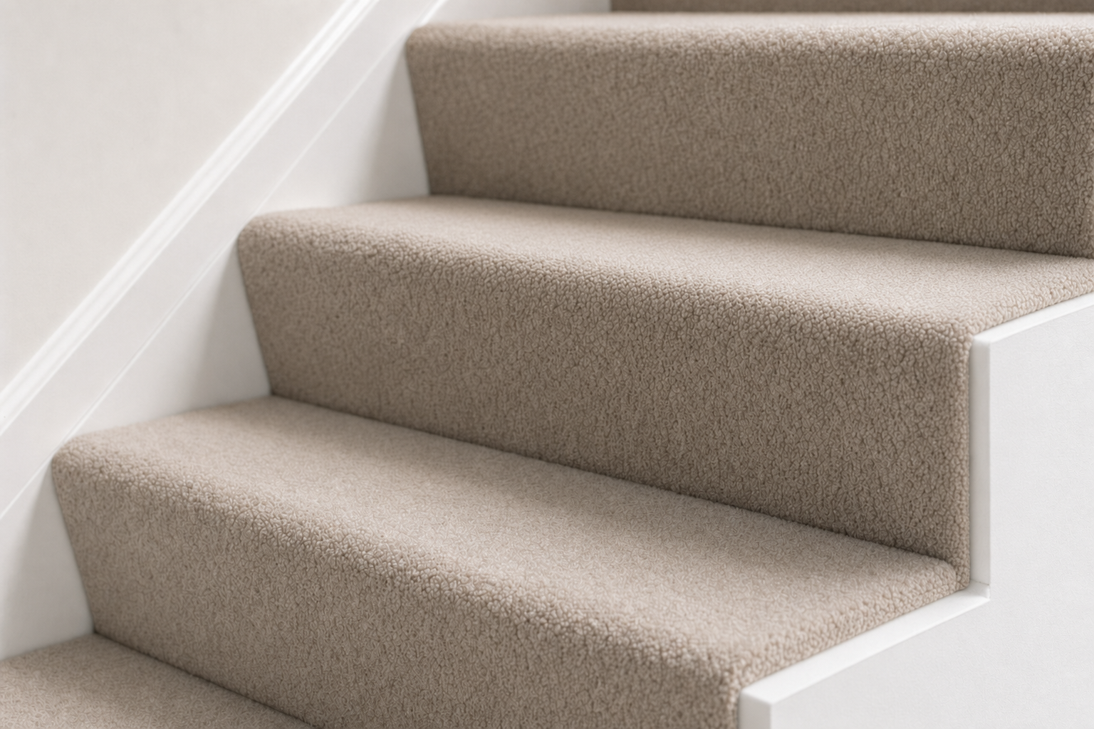 Carpeted staircase with beige upholstery and white skirting boards.
