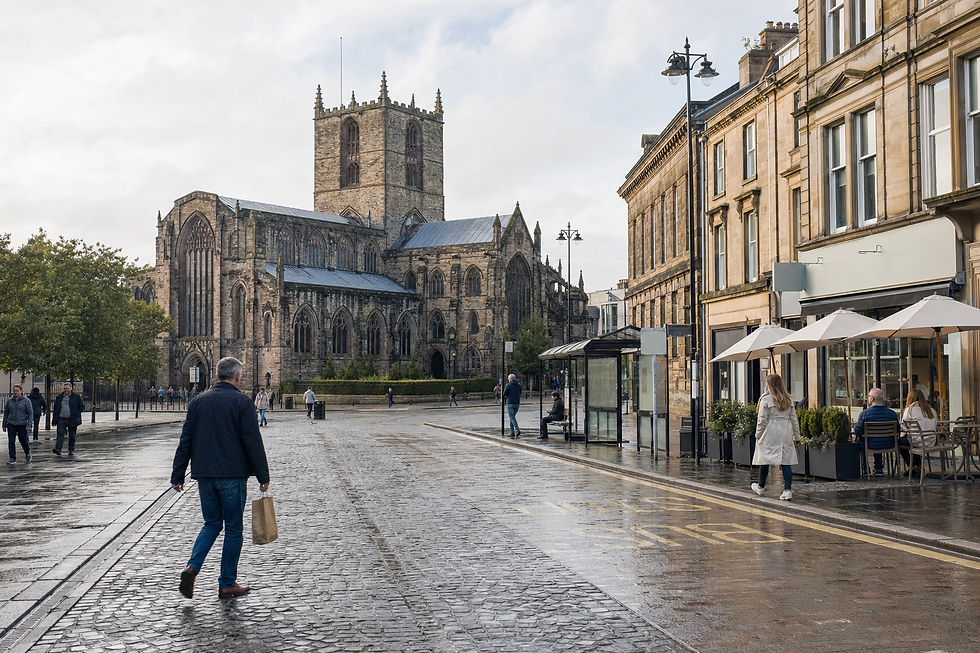 A man walks down a wet street towards a historic cathedral surrounded by buildings and people.