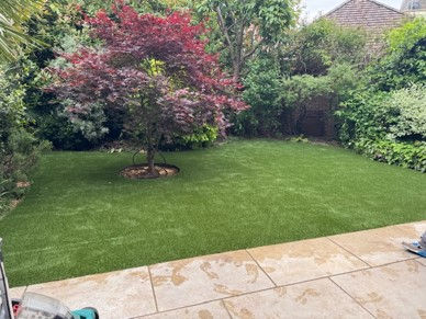patio with artificial turf and trees in the background