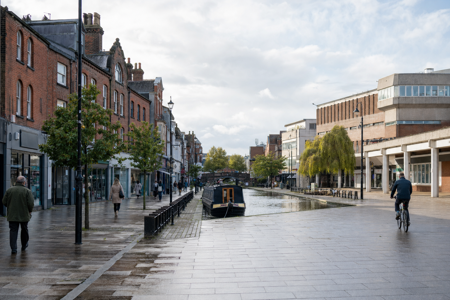 Canal-side street scene with people walking and cycling under a cloudy sky.