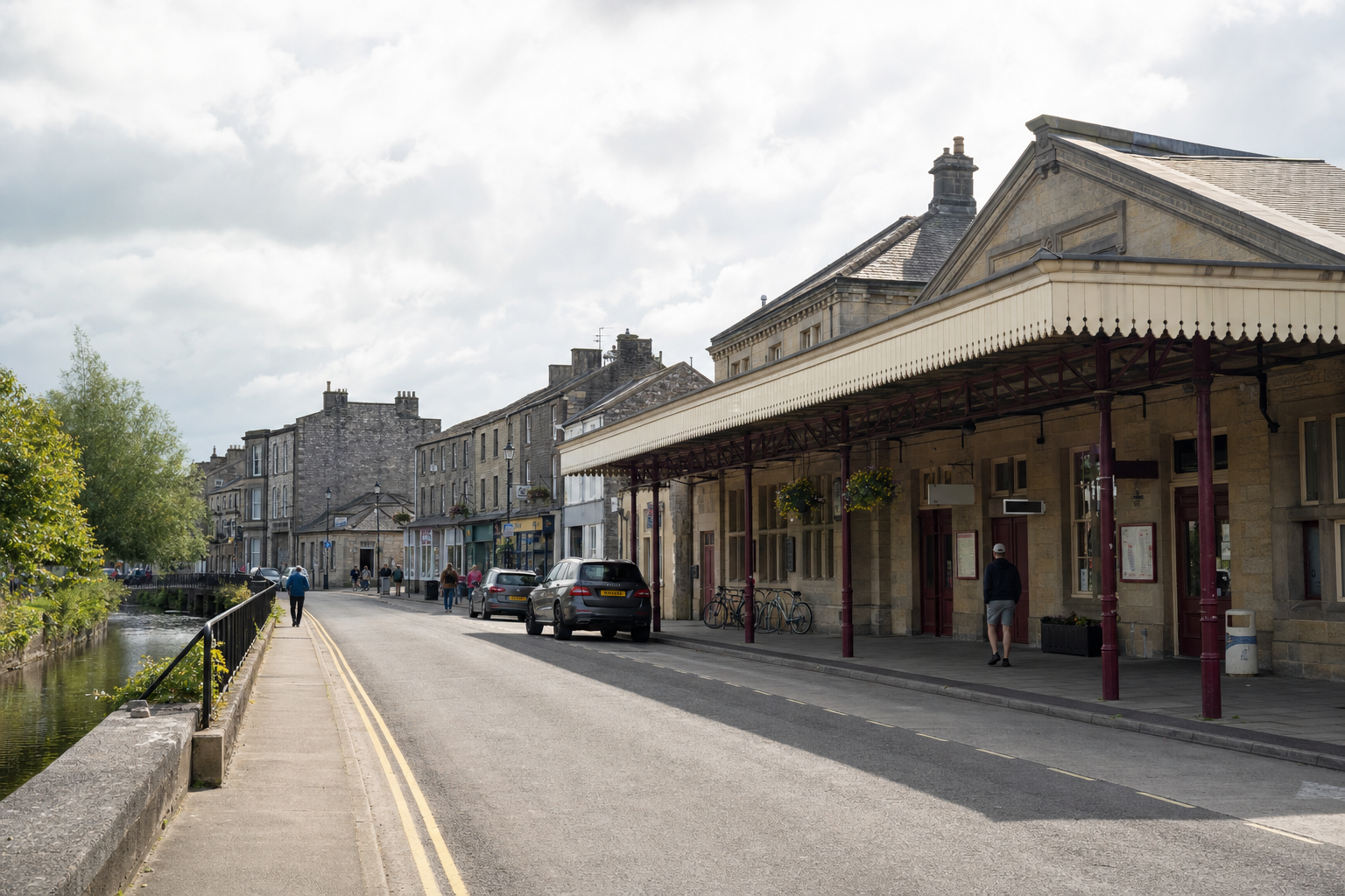 A quiet street in a quaint town with a canal, historic buildings, and a covered walkway.