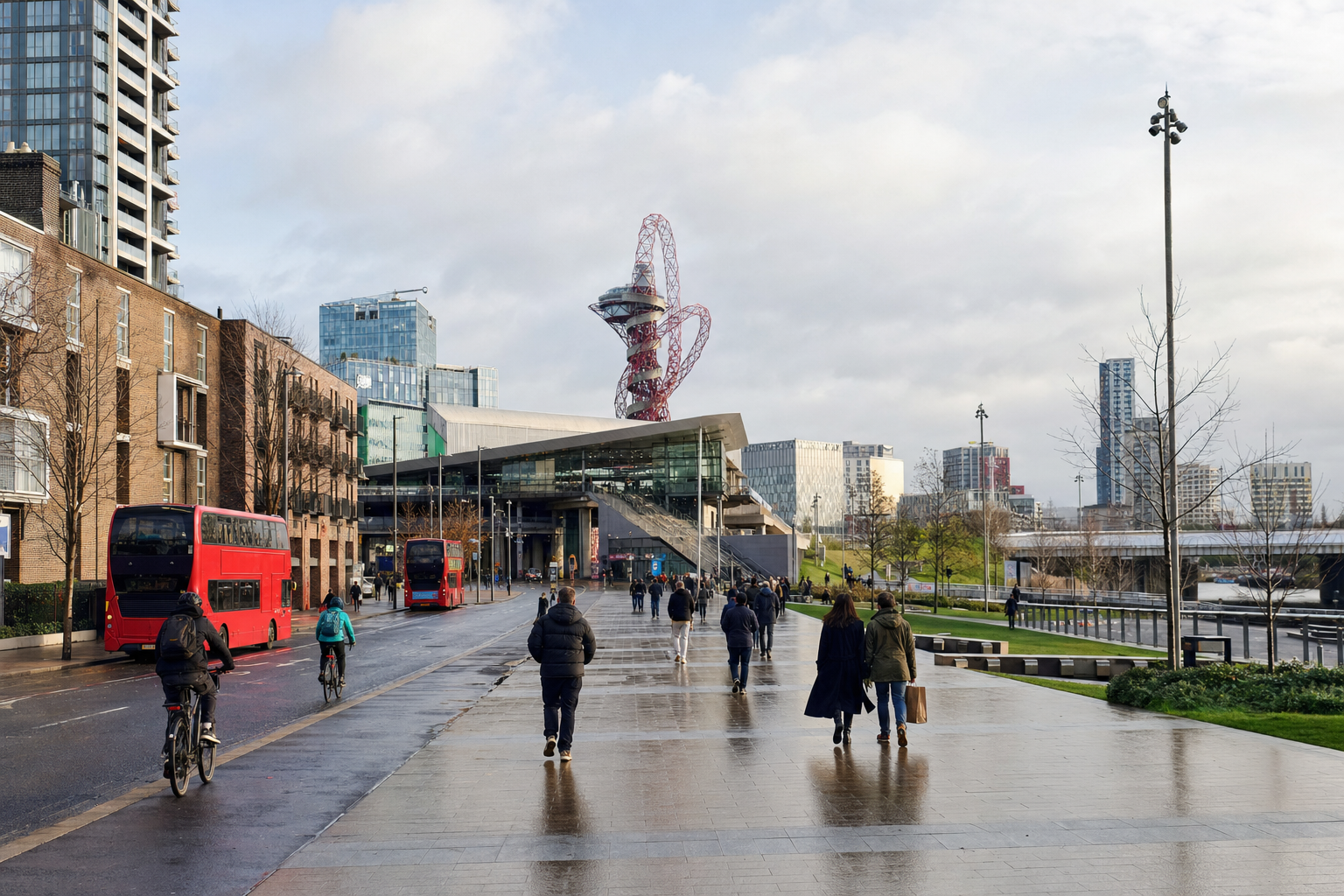 People walking and cycling near the ArcelorMittal Orbit tower in London's Queen Elizabeth Olympic Park on an overcast day.