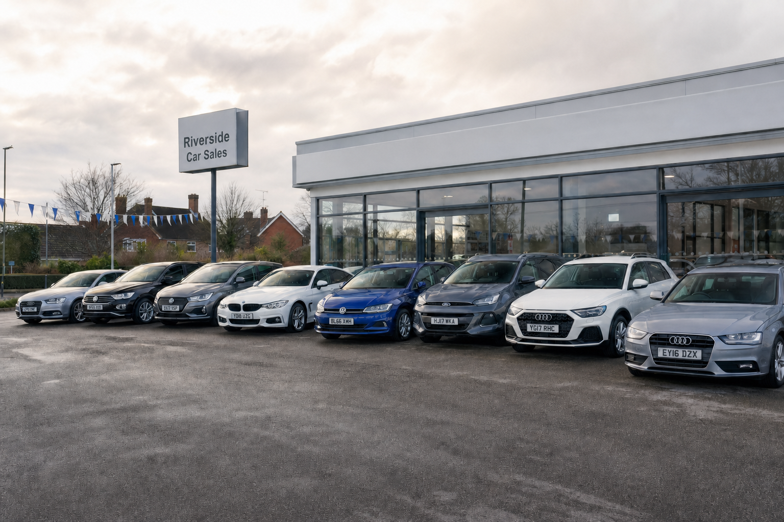 A row of modern cars parked outside Riverside Car Sales dealership under a cloudy sky.