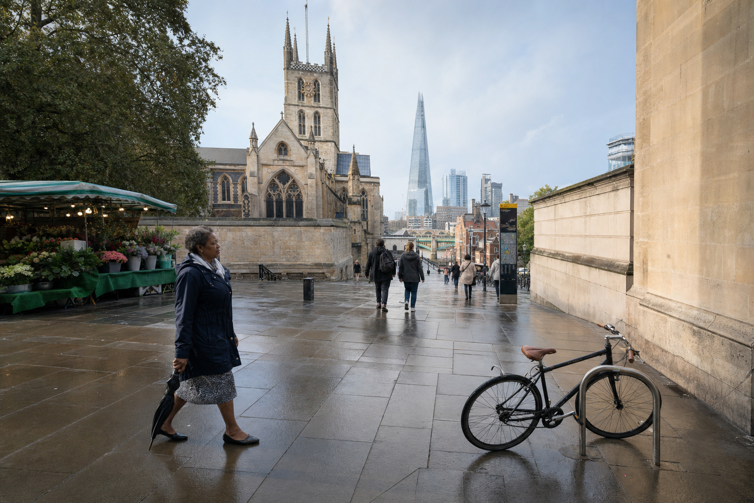 A person walks on a wet street near Southwark Cathedral with the Shard visible in the background.