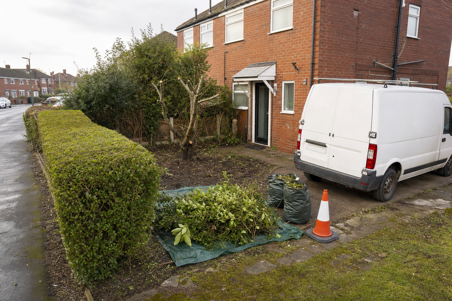 A trimmed hedge and stacked branches in front of a brick house with a white van parked nearby.