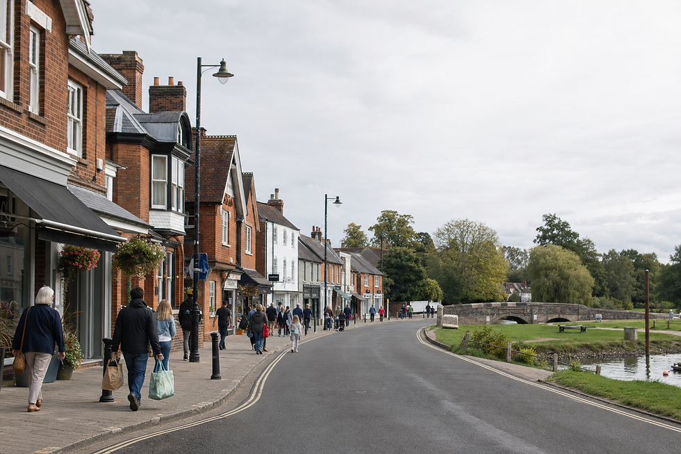 People stroll along a charming street with historic buildings and a riverside view.