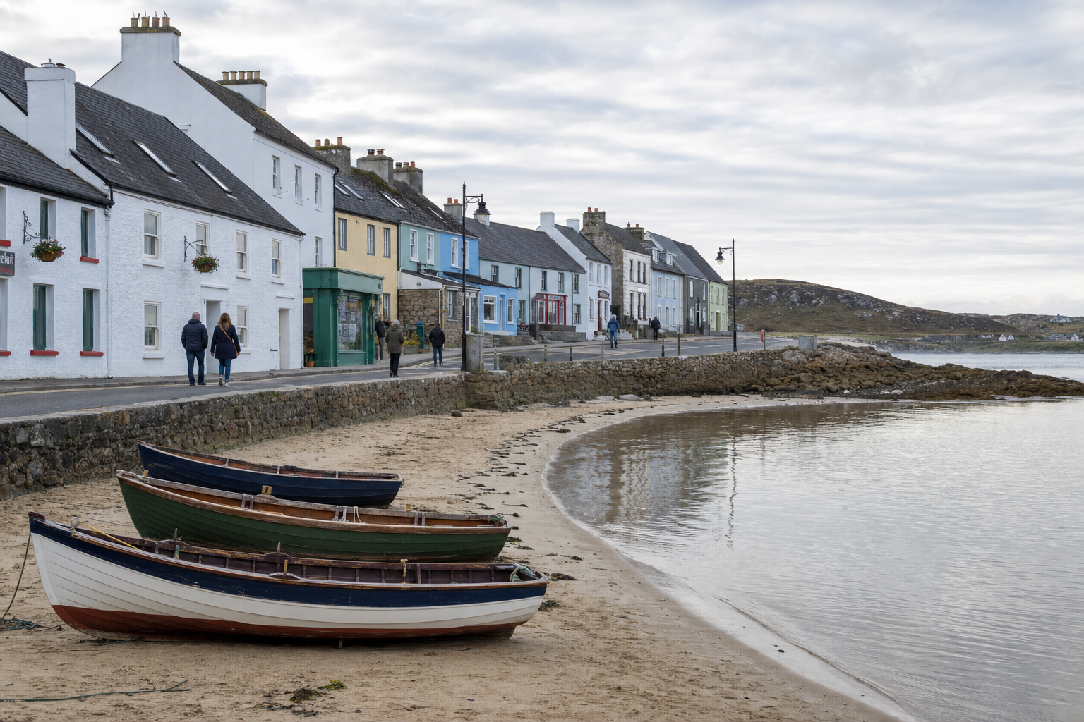 Moored boats on a sandy beach with colourful houses along the waterfront and people walking by.