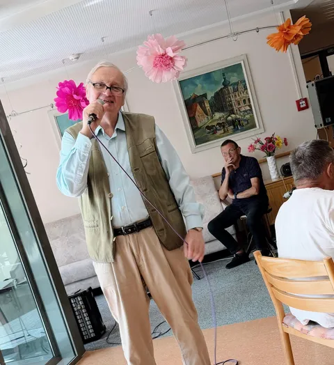 Ein Musiker singt mit Mikrofon vor den Gästen des Sommerfestes im AWO Seniorenzentrum Wohnen im Alter in Sonneberg.
