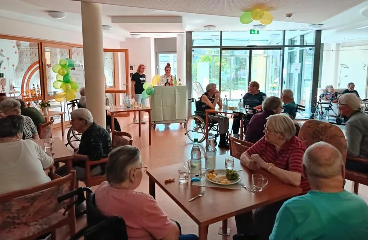 Bewohnerinnen und Bewohner des AWO Seniorenzentrums „Wohnen im Alter“ sitzen während einer gemeinsamen Weinverkostung in geselliger Runde zusammen