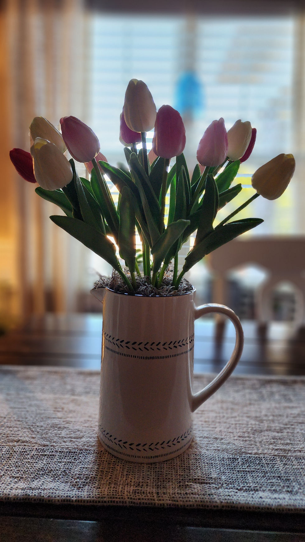 Thumbnail: Realistic tulips are perfectly displayed in a white and blue ceramic vase pitcher. 