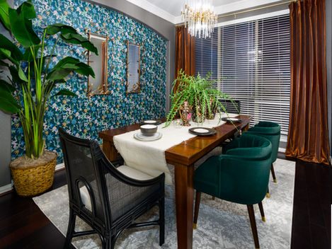 A contemporary dining room with bold wallpaper and green chairs