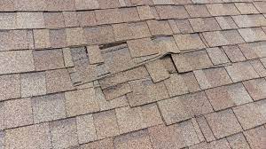 torn shingles from wind on a roof in houston texas storm damage insurance claim