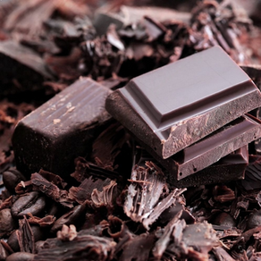 Close-up of dark chocolate bars and shavings in rich brown hues, creating a textured, indulgent scene.