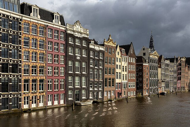 Colorful_canal_houses_at_golden_hour_in_Damrak_avenue_Amsterdam_the_Netherlands.jpg