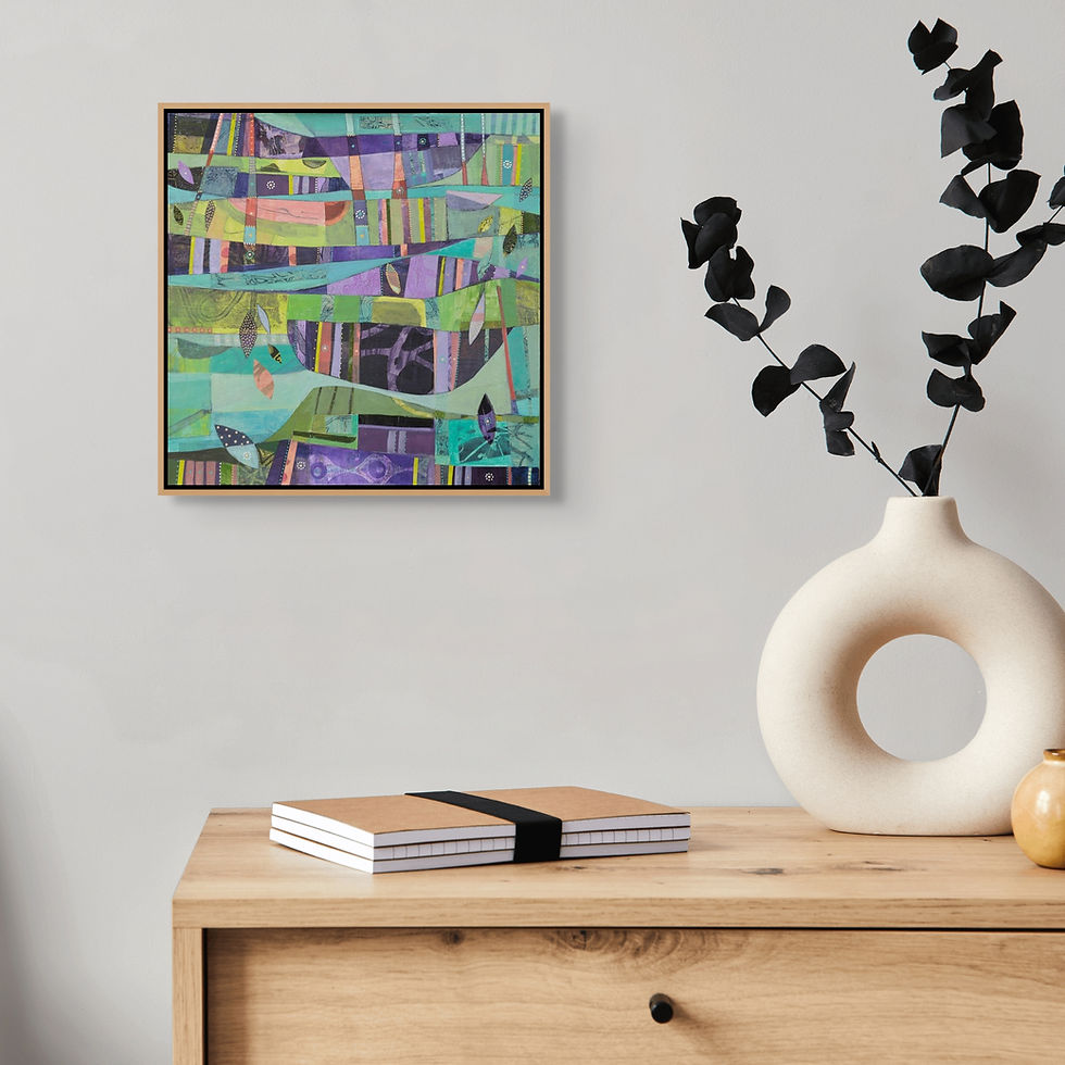 Abstract painting with vibrant colors on a wall above a wooden desk. Vase with black leaves and two notebooks adorn the desk.