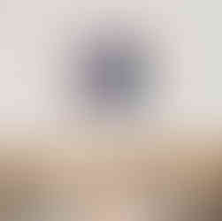 abstract landscape art print in blue and ornage framed in oak above a bed with cushions