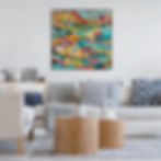 Colorful abstract painting in a modern living room; beige sofa with gray and blue cushions, wooden tables, and decorative items. Cozy ambiance.