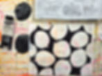 Black paint tube, leaf stencils, and abstract circles on a colorful, paint-splattered surface; artistic and creative setting.