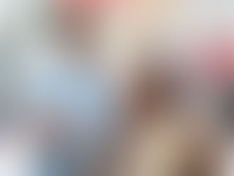 戶外廣場上,一位穿黃白條紋上衣的女子坐在秋千上微笑仰望,身後有一名男子虛化站立,畫面明亮輕鬆。