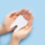 Woman hand holding healthy white teeth symbol on light blue background Dental care, tooth