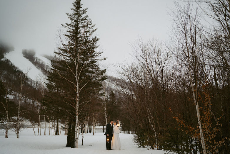 Couple exploring with lanterns in the white mountains on a winter elopement day.